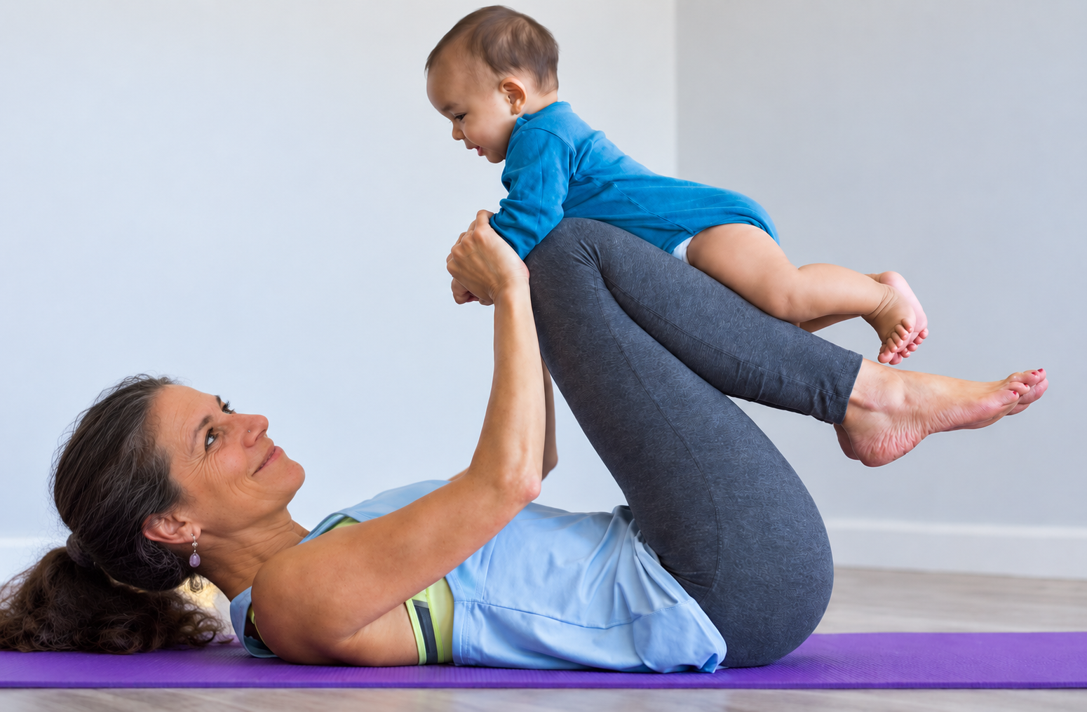 A parent and baby bonding together during parent and baby yoga on a yoga mat